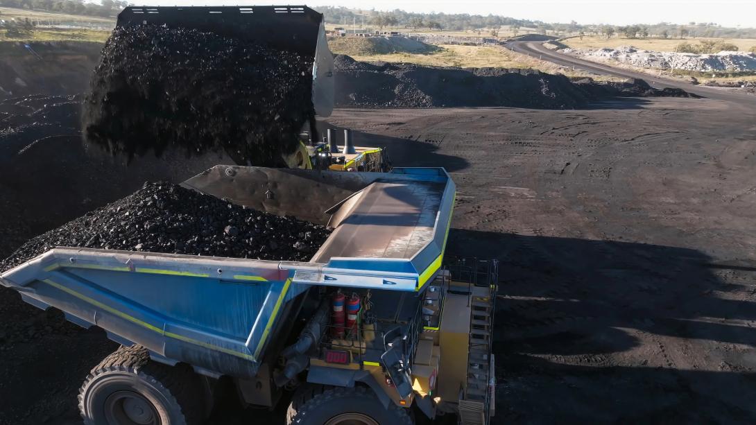 Front-end mining loader extracting and loading coal onto truck