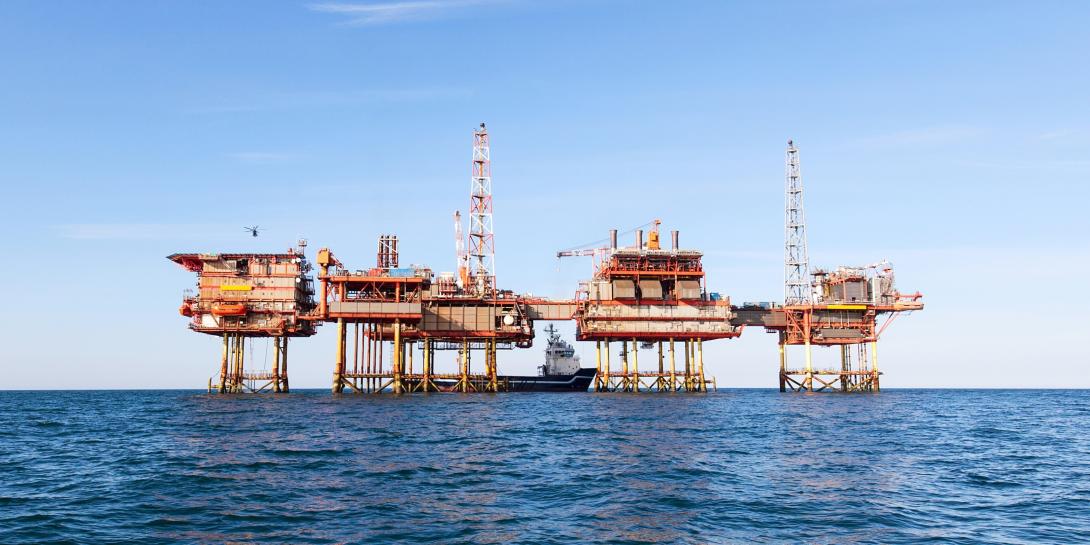 Picture of an offshore LNG facility in the ocean against a clear blue sky